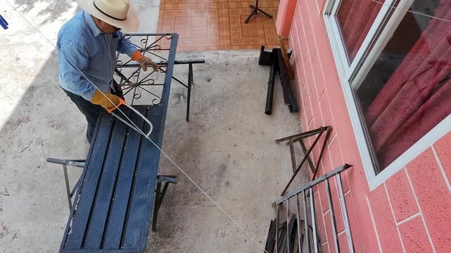 Drone Aerial View of Worker Manually Sawing Metal Door Frame with Hacksaw