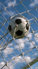 Fototapeta premium Soccer ball stuck in goal net against blue