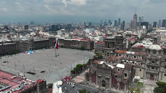 A breathtaking cinematic aerial timelapse capturing the fluid movement of pedestrians and traffic across the massive Z&oacute;calo plaza, framed by the monumental architecture of the Metropolitan Cathedral.