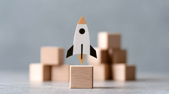 A miniature rocket stands poised for launch atop a wooden block  surrounded by other blocks in soft focus