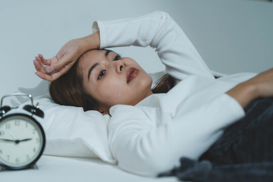Young woman sleepless during night time on the bed.