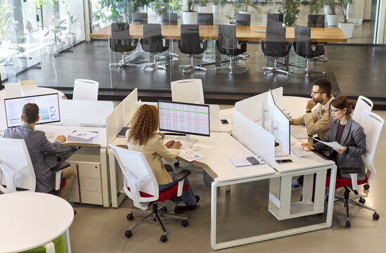 Team analysts accountants in office with computers. Businesspeople review data charts and reports, planning budgets and tracking results. Finance teamwork collaboration and analysis concept.