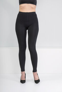 Woman wearing tight black medical compression leggings with high heels. Hosiery for varicose vein treatment and blood circulation support. Recovery clothing after leg surgery or injury