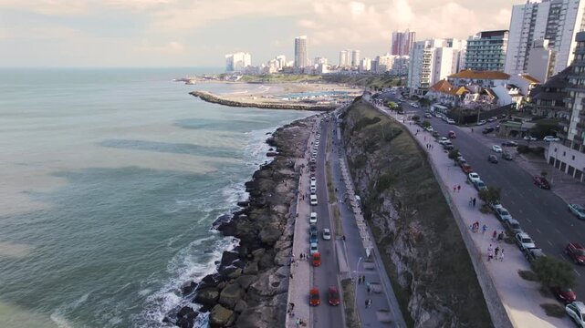 4K drone aerial view of the coastal road in Mar del Plata, Argentina. The scenic waterfront avenue follows the Atlantic coastline with urban buildings, beaches and the city stretching into the distanc