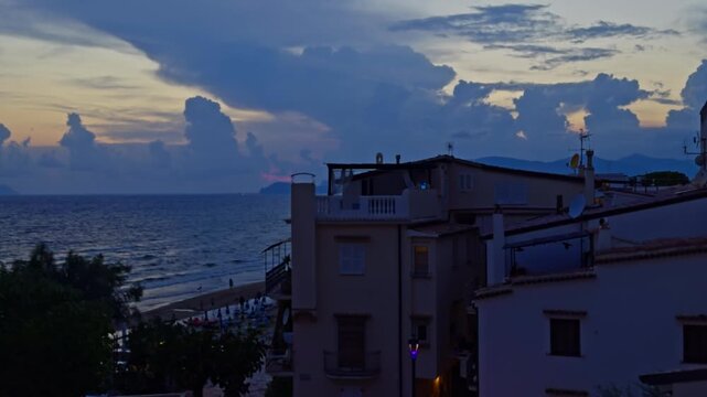 Picturesque view of the coastal town of sperlonga in latium, italy. The sea waves gently crash on the beach under a dramatic sky at twilight