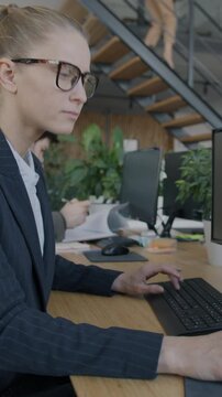 Young businesswoman working with personal computers in open space office focused on business report. Professional occupation and modern technology concept.