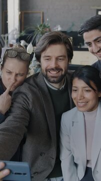 Slow motion of playful businesspeople taking selfie with smartphone camera posing having fun in office. Business and photo concept.