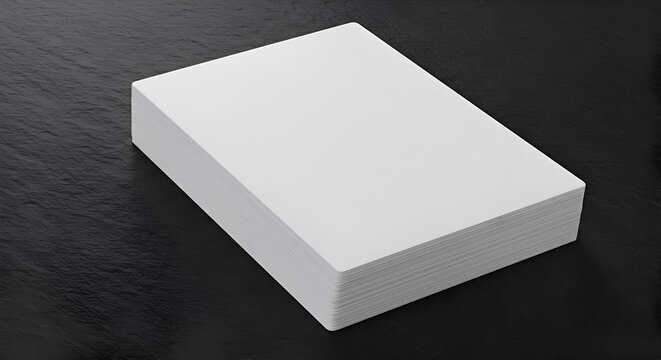 Stack of blank white paper on dark stone surface. High angle view of a stack of pristine white paper resting on a dark, textured stone surface.