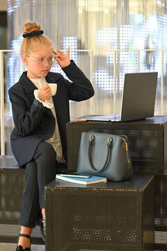 A little girl is looking at an open laptop.