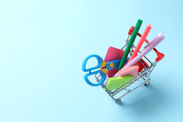 School stationery supplies in mini cart on blue background © Sunlight