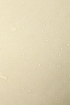 Top view photo of small drops of water on beige background. Vertical view