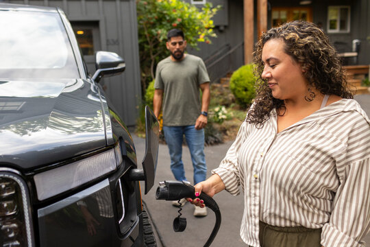 Woman charging an electric vehicle in her driveway