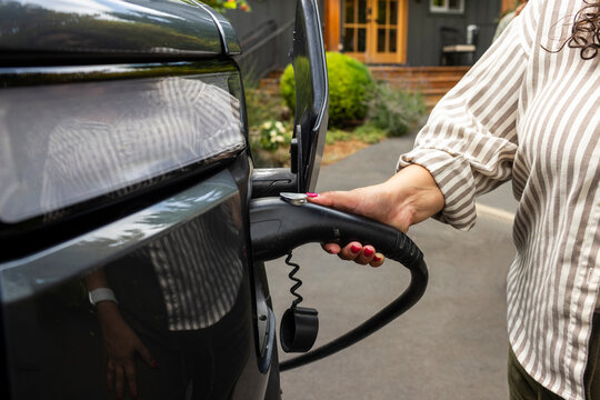 Woman charging her electric vehicle at home