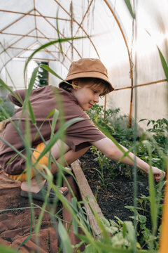 Happy young boy tending to plants in a greenhouse