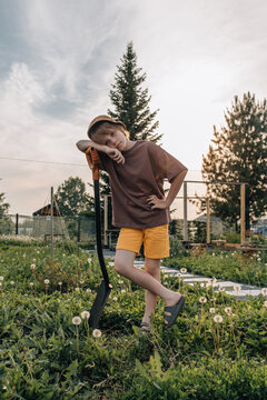 Young boy leans on a shovel in a backyard garden