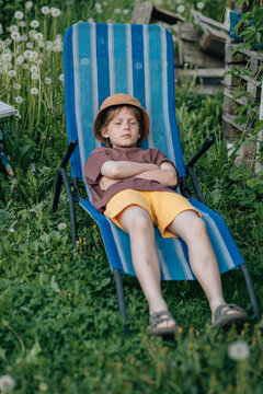 Young boy taking a nap in a striped lawn chair