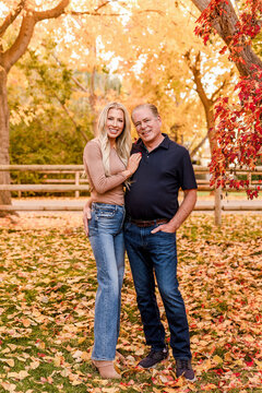 Happy couple posing amongst colorful autumn leaves