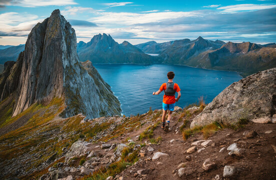 Man trail running along a scenic mountain ridge with Segla
