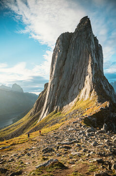 Two hikers dwarfed by a giant mountain peak Segla