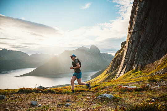 Man trail running along a mountain ridge at sunset