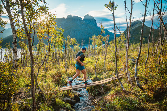 Trail runner crosses a plank bridge in the mountains