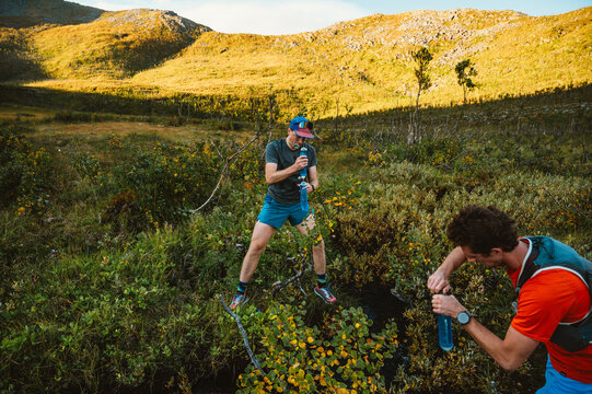 Male runners filtering water from a mountain creek