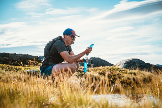 Hiker filters fresh water from a mountain stream