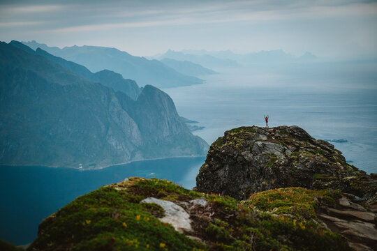 Hiker celebrates on mountaintop with an epic fjord view