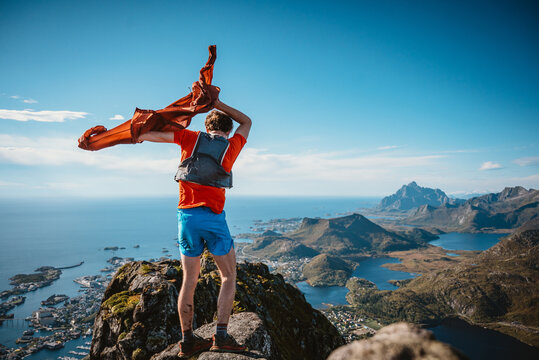 Trail runner celebrates on a mountain summit above the fjords