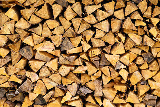 Close-up view of neatly stacked split firewood logs showing textured wooden grain and rings