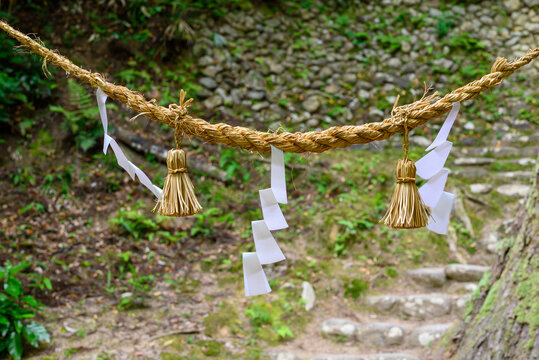 Close-up view of a traditional Japanese Shinto shimenawa sacred straw rope with white shide paper streamers in a shrine