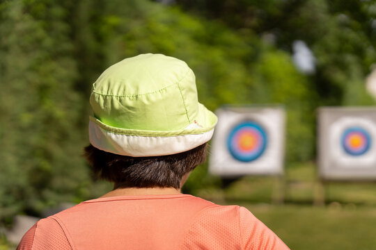 Person wearing bucket hat concentrating on archery target during practice session