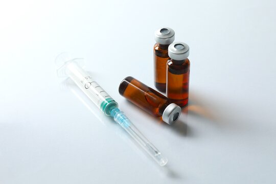 Vaccine in vials and a syringe on a white background, flat lay. 