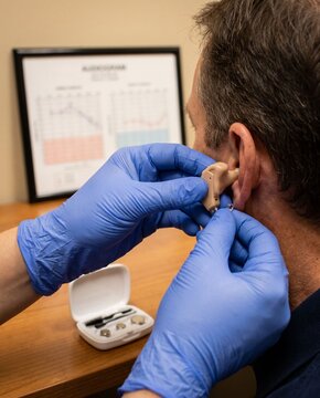 Healthcare professional fitting hearing aid on a patient