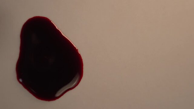 Red blood pooling on surface in slow motion, top view off-center left layout, eerie feeling for horror and crime scene background⁠