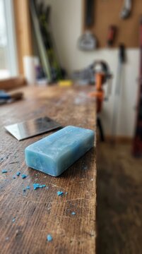 A block of blue alpine ski wax resting on a rustic wooden workbench