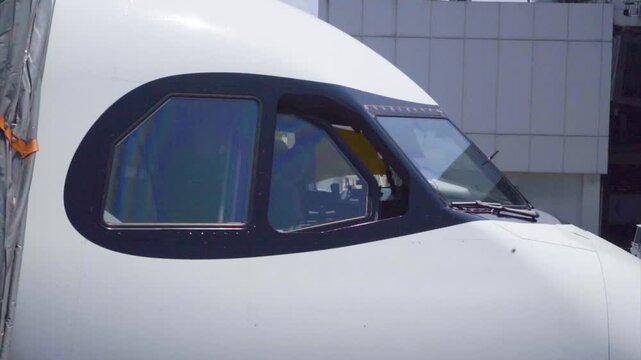 Close up shot of modern jet airliner cockpit window section connected to boarding bridge at airport terminal gate stock video footage