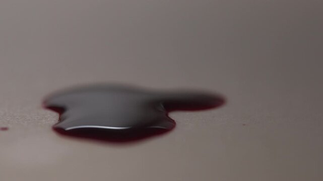 Ominous suspenseful vibe in macro side view zoom in of red blood pool dripping on white surface, ideal for horror and cinematic close-up for crime scene