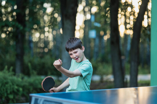 Excited boy celebrates a table tennis victory outdoors