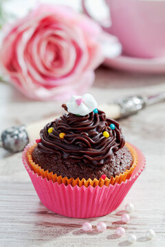 Decorated chocolate muffin in muffin paper on laid table