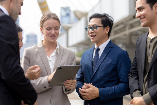 Business teamwork concept. diverse professional colleagues discussing ideas and sharing tablet outdoors in corporate district. teamwork, business, team, collaboration, tablet.