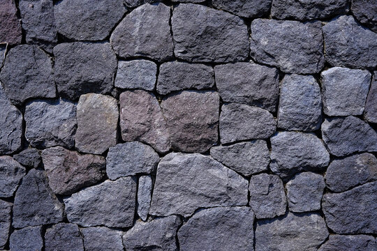 Horizontal view of a rustic dry stone wall texture built with interlocking grey rocks. Photographed in Purwodadi Botanical Garden, Pasuruan, Indonesia on July 4, 2025.