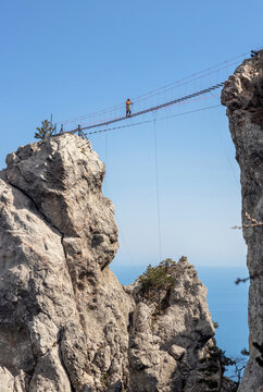 A brave man walks on a tightrope high up in the rocky mountains