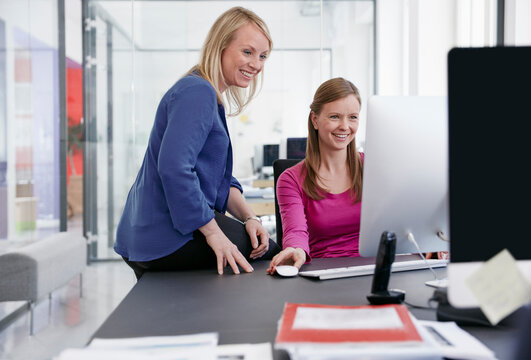 Two women working at computer in office