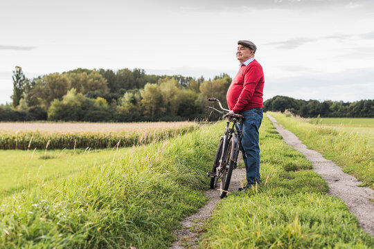 Senior man with bicycle in rural landscape