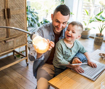 Father and son having fun controlling smart home light with app at home