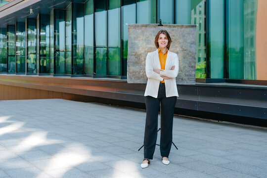Confident businesswoman poses outdoors against a canvas background