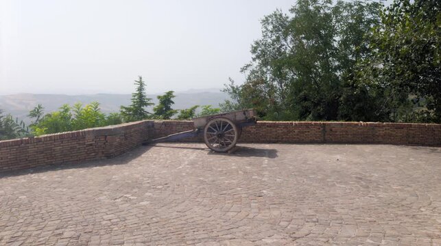 Inquadratura di un vecchio biroccio su una terrazza panoramica in pietra con vista sulle colline della Romagna
