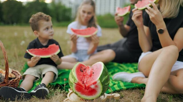 Macro view of fresh watermelon with eating family in the blurred background.