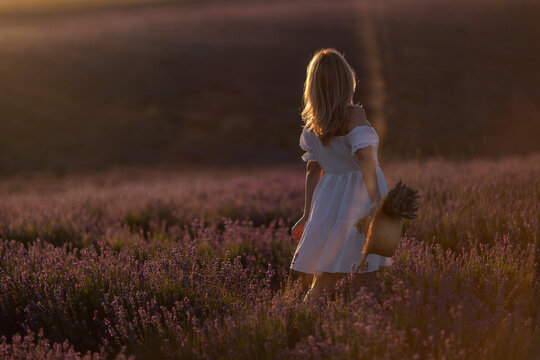 Woman lavender sunset walking through golden field holding flower basket copy space